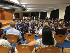 students and teachers sitting at a primary school assembly